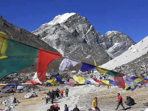 Fluttering colorful prayer flags, stunning Lobuche East Peak in the background.